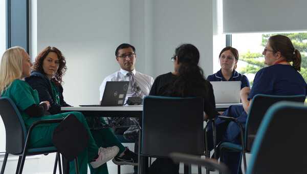 Photograph of a group of people sitting around a table talking with each other