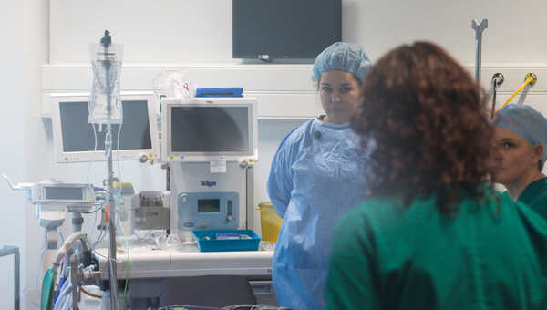 Photograph of a surgical theatre with a number of people in gown talking with each other