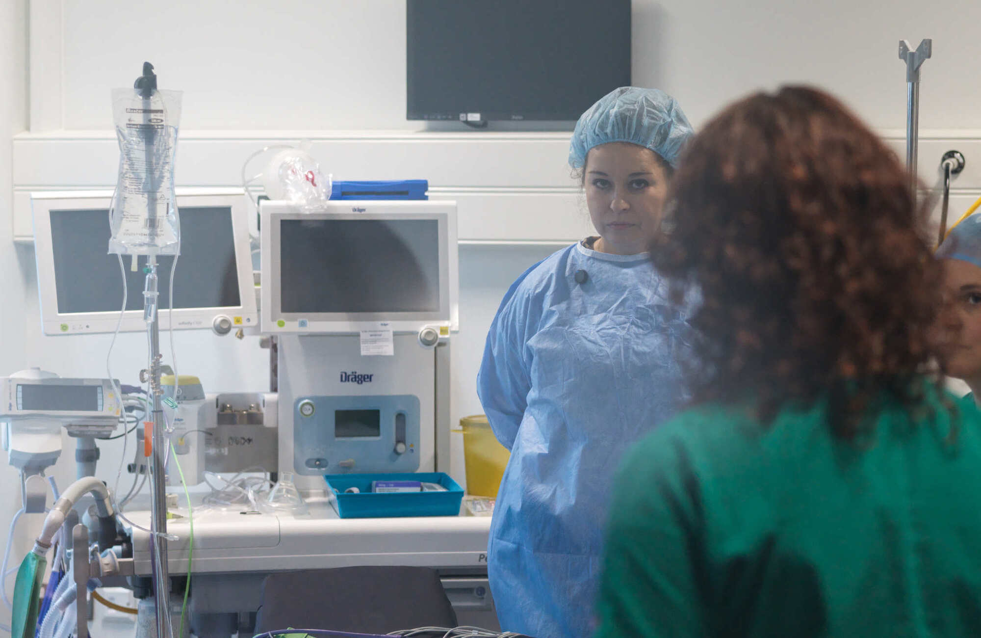 Photograph of a surgical theatre with a number of people in gown talking with each other