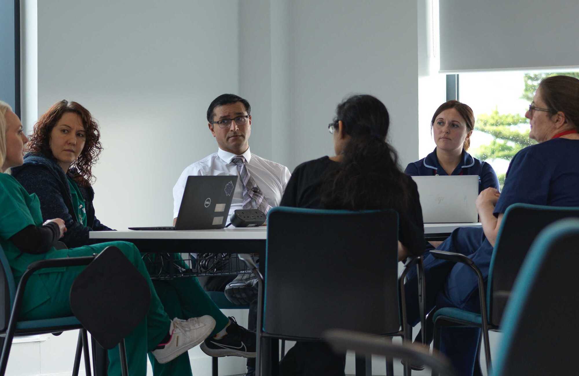 Photograph of a group of people sitting around a table talking with each other