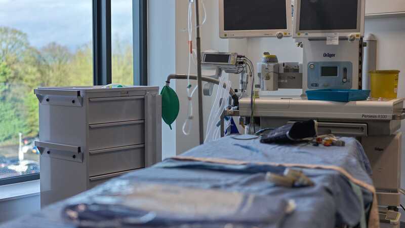 Photograph of an empty surgical bed with medical machines in the background.