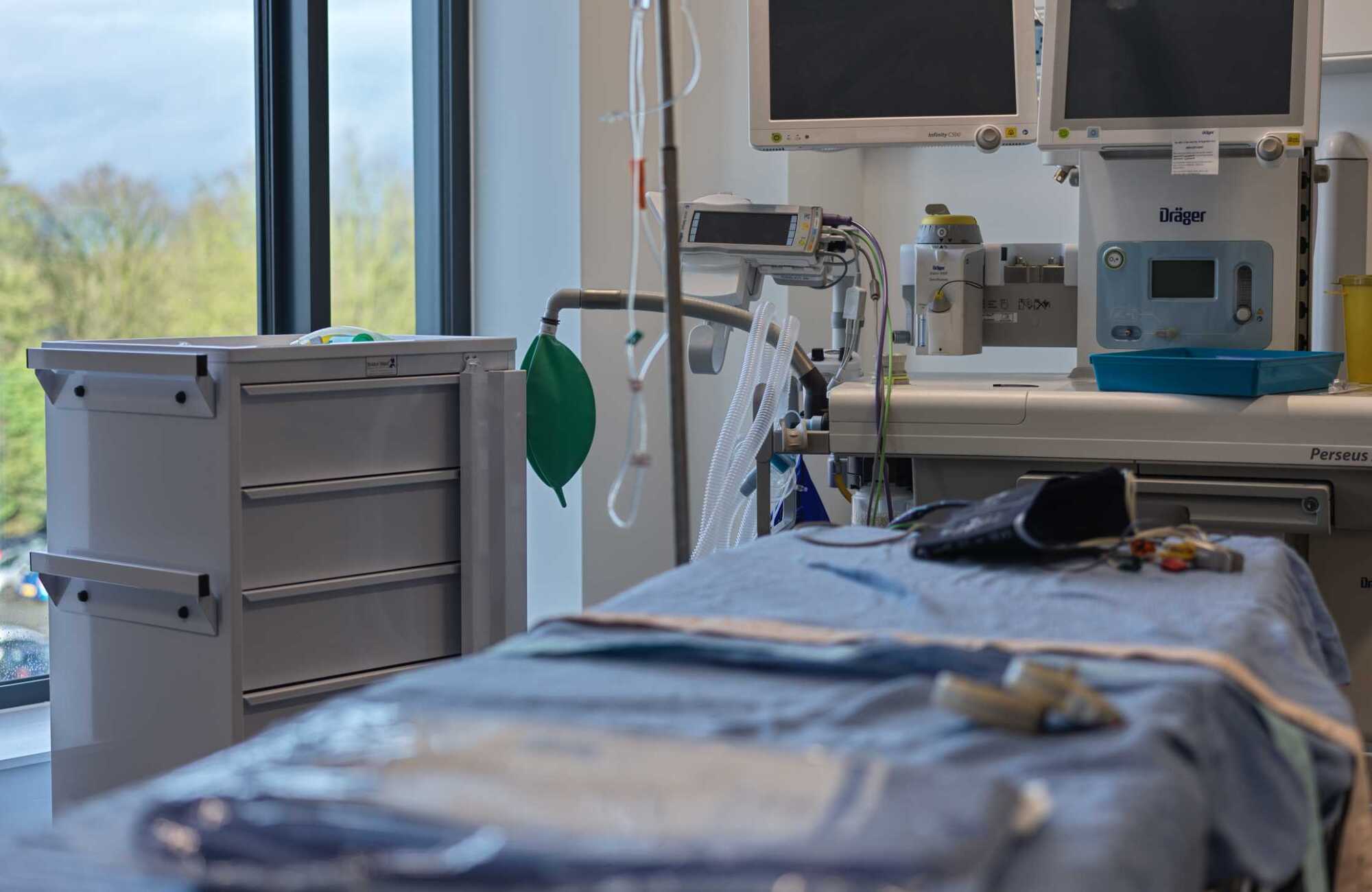 Photograph of an empty surgical bed with medical machines in the background.